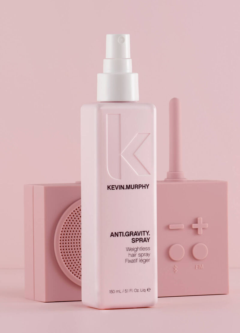 Kevin Murphy Anti-Gravity Hair Spray bottle in light pink, styled with two matching pink decorative blocks behind it on a solid pink background.