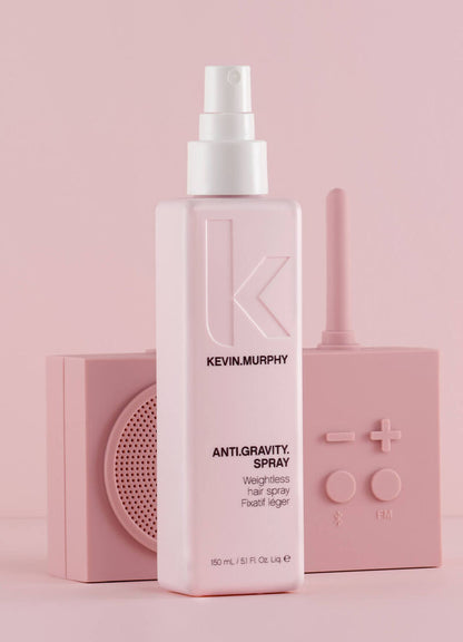 Kevin Murphy Anti-Gravity Hair Spray bottle in light pink, styled with two matching pink decorative blocks behind it on a solid pink background.